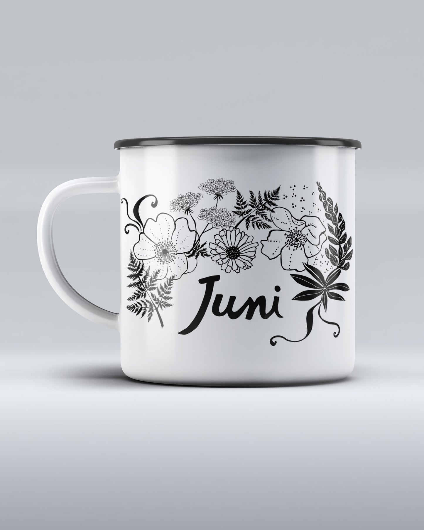 
                  
                    White enamel mug with dark rim, decorated with a botanical black-and-white illustration of wild flowers, ferns, and the word Juni in calligraphy, from the book Nature Is Your Friend by Lisa Grue
                  
                
